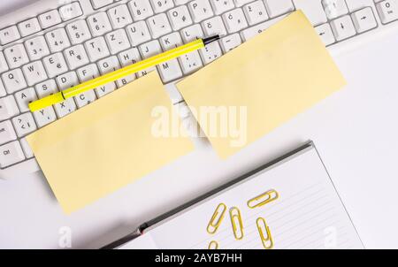 Flat lay above blank note papers on the business concept table. Empty orange square paper by the pc keyboard with copy space. Stock Photo