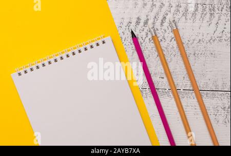 Closeup front view blank spiral notepad pencils markers highlighters ballpoints letter size colored paper sheet wooden retro bac Stock Photo