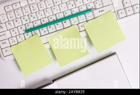 Three empty green square papers by the pc keyboard with copy space. Flat lay above blank note papers on the business concept tab Stock Photo