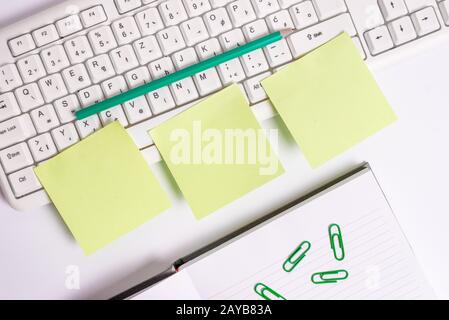 Flat lay above blank note papers on the business concept table. Three empty green square papers by the pc keyboard with copy spa Stock Photo