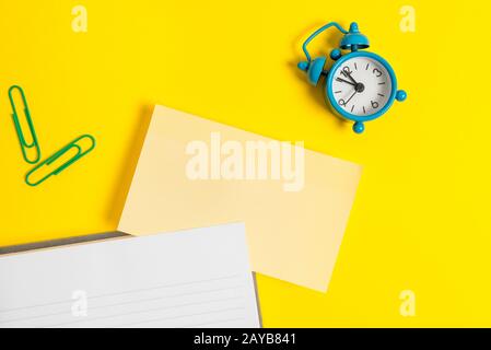 Blank paper for text messages. Empty orange paper with copy space and paper clips on the yellow table. Business concept with bla Stock Photo