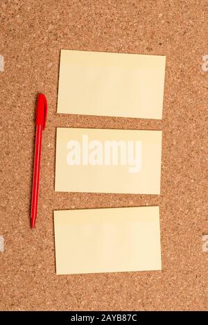 Corkboard desk with three vertical empty sticker notes, office appliances and study supplies. Billboard with upright, square sha Stock Photo