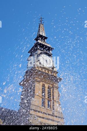 blurred splashing water from a fountain in front of the clock tower of the historic atkinson building in southport merseyside Stock Photo