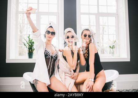 Picture showing group of happy friends in spa. girls with towels on heads having fun and taking selfie at home. Friendship, cosm Stock Photo