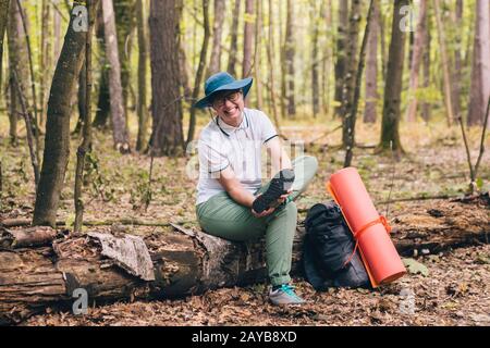 Young woman having trouble feeling knee pain during travel in forest. Injury on way to camp. female tourist got leg injury in fo Stock Photo