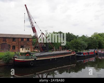 barges and houseboats on the aire and calder navigation canal at stourton leeds with and old crane and the historic thwaite mill Stock Photo