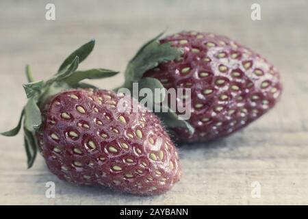 Two strawberries on the surface of the wooden table. Stock Photo