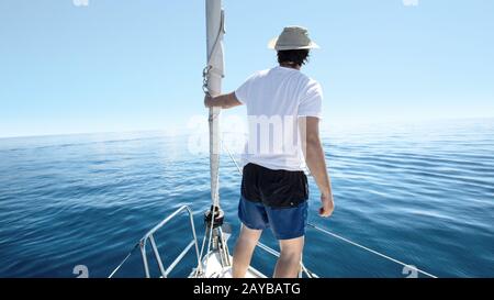 Man standing at the bow of a ship. Yachting, vacation and freedom concept. Stock Photo