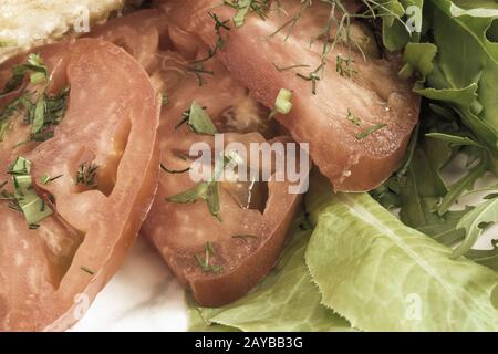 Sliced tomatoes next to lettuce and parsley. Stock Photo
