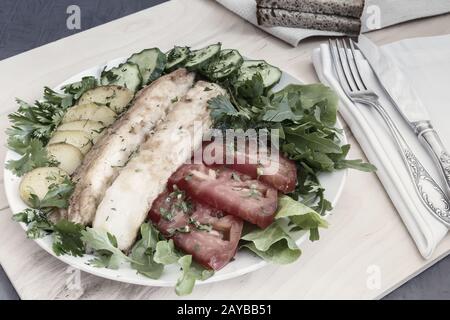 Fried fish with potatoes, vegetables and herbs Stock Photo