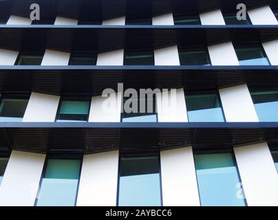 facade of a futuristic modern building with angled geometric panels and rows of reflected windows Stock Photo