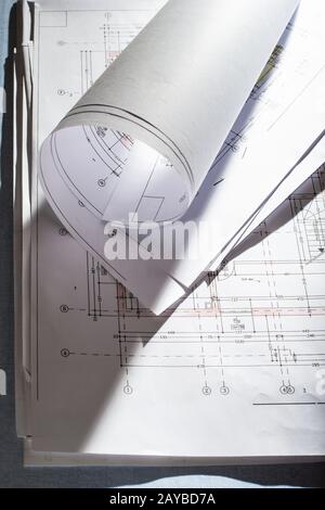 Blueprints on architect desk. Stacked and rolled up architectural projects on natural window light. Stock Photo