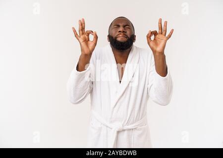 Young African man in bathrobe prepare for skin care showing ok finger sign. Human emotions concept Stock Photo