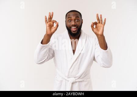 Young African man in bathrobe prepare for skin care showing ok finger sign. Human emotions concept Stock Photo
