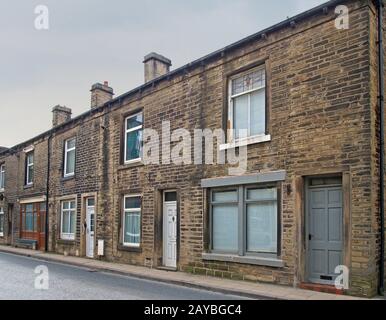 a row of traditional english old working class terraced houses on a street with grey cloudy sky Stock Photo