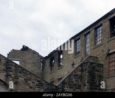 an old ruined abandoned large industrial building with burned out broken windows collapsing walls Stock Photo