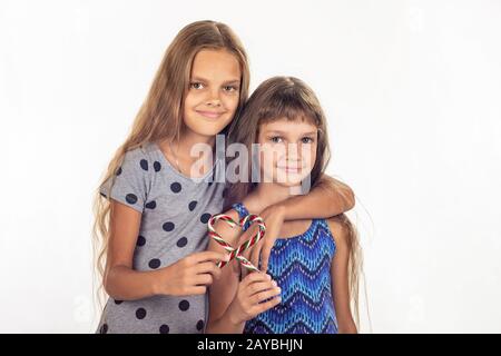 Two girls hugging made a heart out of two lollipops Stock Photo