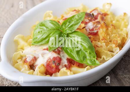 gratinated pasta on wood with wine Stock Photo
