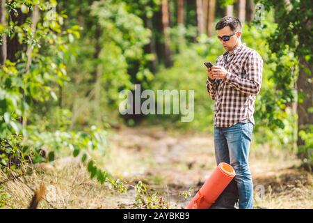 Hipster young man with backpack using smart phone on beautiful nature.Travel concept. Outdoor travel. Travel and explore. Backpa Stock Photo