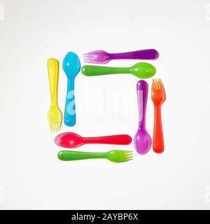 Square from colorful plastic cutlery on a light background. Stock Photo