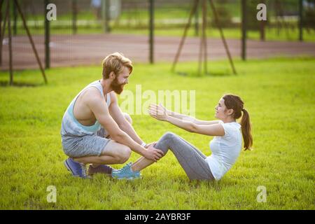 Sit ups fitness couple exercising sit up outside in grass. Fit people working out cross training. Woman doing abdominal crunches Stock Photo