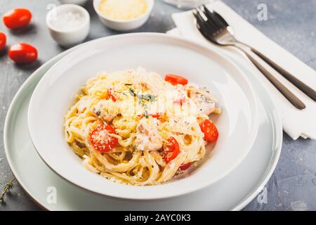 Delicious salmon linguine pasta dish with herbs and grilled salmon filet. Stock Photo