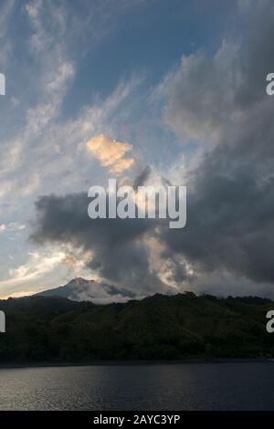 View of Sangeang Api Volcano Island near Sumbawa Island, Lesser Sunda Islands, Indonesia, with the volcano covered by clouds. Stock Photo