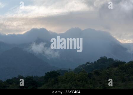 View of Sangeang Api Volcano Island near Sumbawa Island, Lesser Sunda Islands, Indonesia, with the volcano covered by clouds. Stock Photo