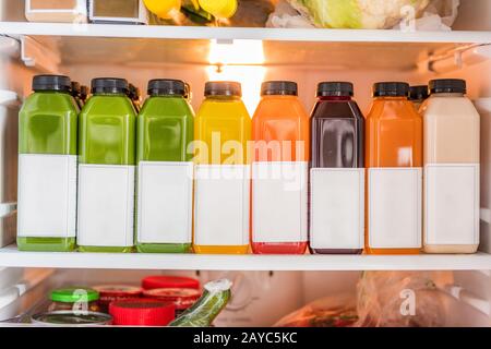 Juicing cold pressed vegetable juices for a detox cleanse diet. Dieting bydrinking organic fruits and vegetables juice made fresh and delivered in bottles at home in fridge. Stock Photo
