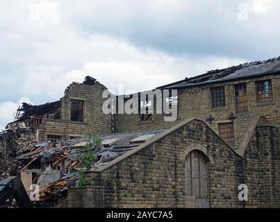 a large ruined industrial destroyed by a fire with collapsing walls and roof and burned timbers Stock Photo