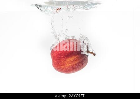 Apple falls under water with a splash. Stock Photo