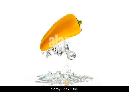 Yellow paprika falls under water with a splash. With lots of air bubbles upside down Stock Photo
