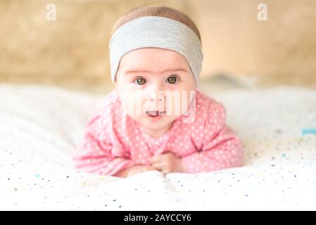 Adorable baby girl with grey headband looking towards camera and smiling. Health concept Stock Photo