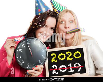 Two women holding a chalkboard and a clock isolated on white background. New year 2020 concept. Stock Photo