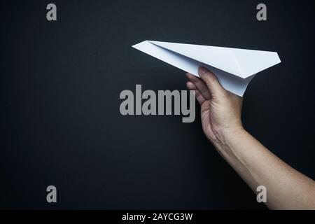 Hand holding paper airplane on black background Stock Photo