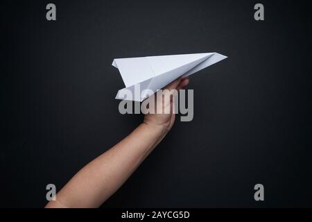Hand holding paper airplane on black background Stock Photo