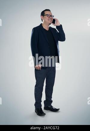 Happy smiling businessman wearing black suit and using modern smartphone Stock Photo