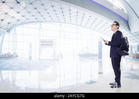 Young business man using digital pad smiling happy inside  airport waiting hall  . Stock Photo