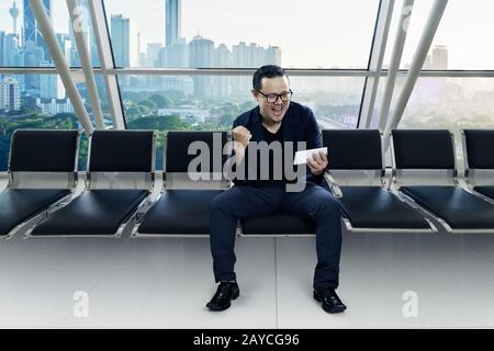 Young excited businessman sitting in the conference room by using smart phone to know his business is success . Day scene . Stock Photo