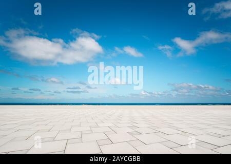Outdoor empty square marble floor and sea under the blue sky . Stock Photo