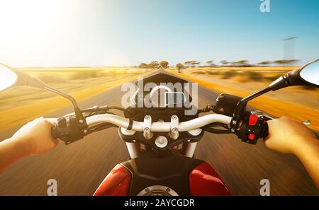 Biker driving a motorcycle rides along the country road Stock Photo