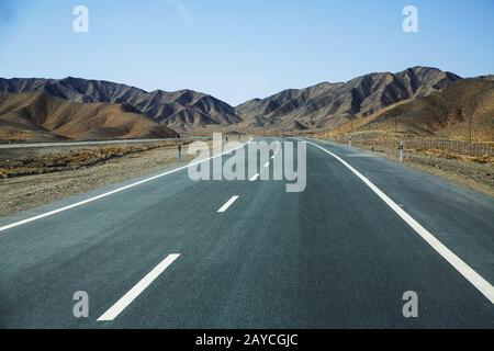 Long empty asphalt road in desert with  clear blue sky . Stock Photo