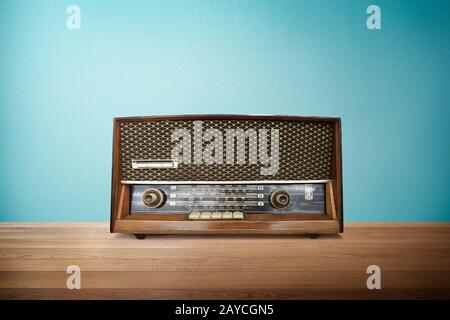 Old vintage retro broadcast radio on wood table with mint blue background . Stock Photo