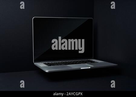 Laptop floating on mockup three dimensional black background Stock Photo