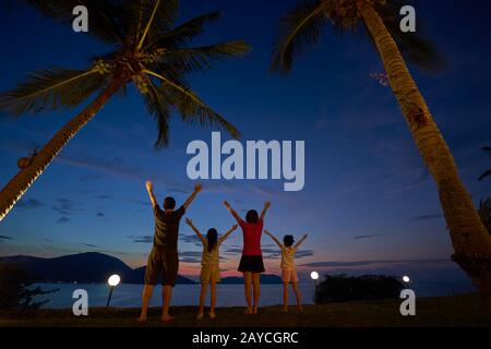 The family raised their hands and cheered to enjoy the seaside at dusk
