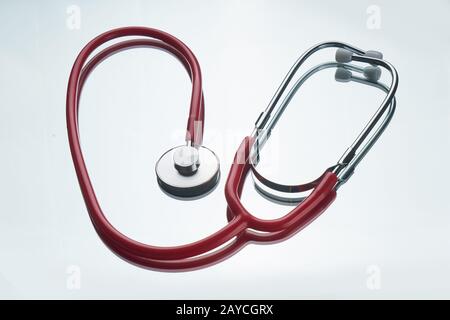 Red color stethoscope with reflection on glossy background. Stock Photo