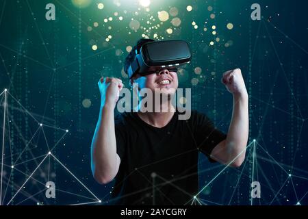 Asian man wearing virtual reality goggles in cyberspace imaging. Stock Photo