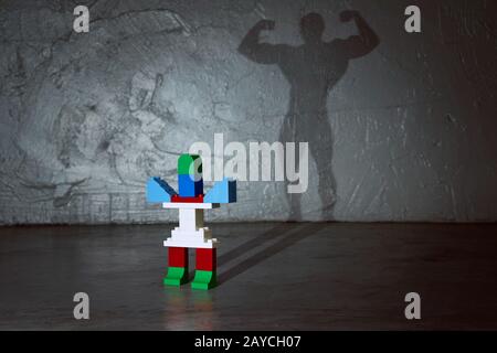 Plastic building blocks with muscle man shadow . Creative and ideal concept . Concrete interior background . Stock Photo