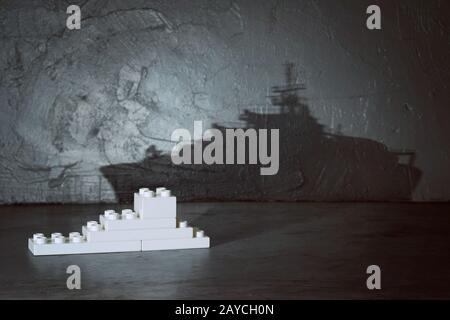 Plastic building blocks with ship shadow . Creative and ideal concept . Concrete interior background . Stock Photo