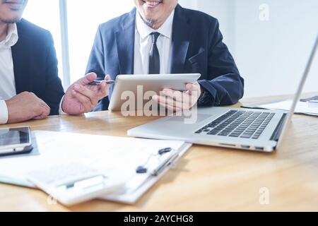 Two businessman using digital tablet and laptop discussing ideal at meeting . Stock Photo